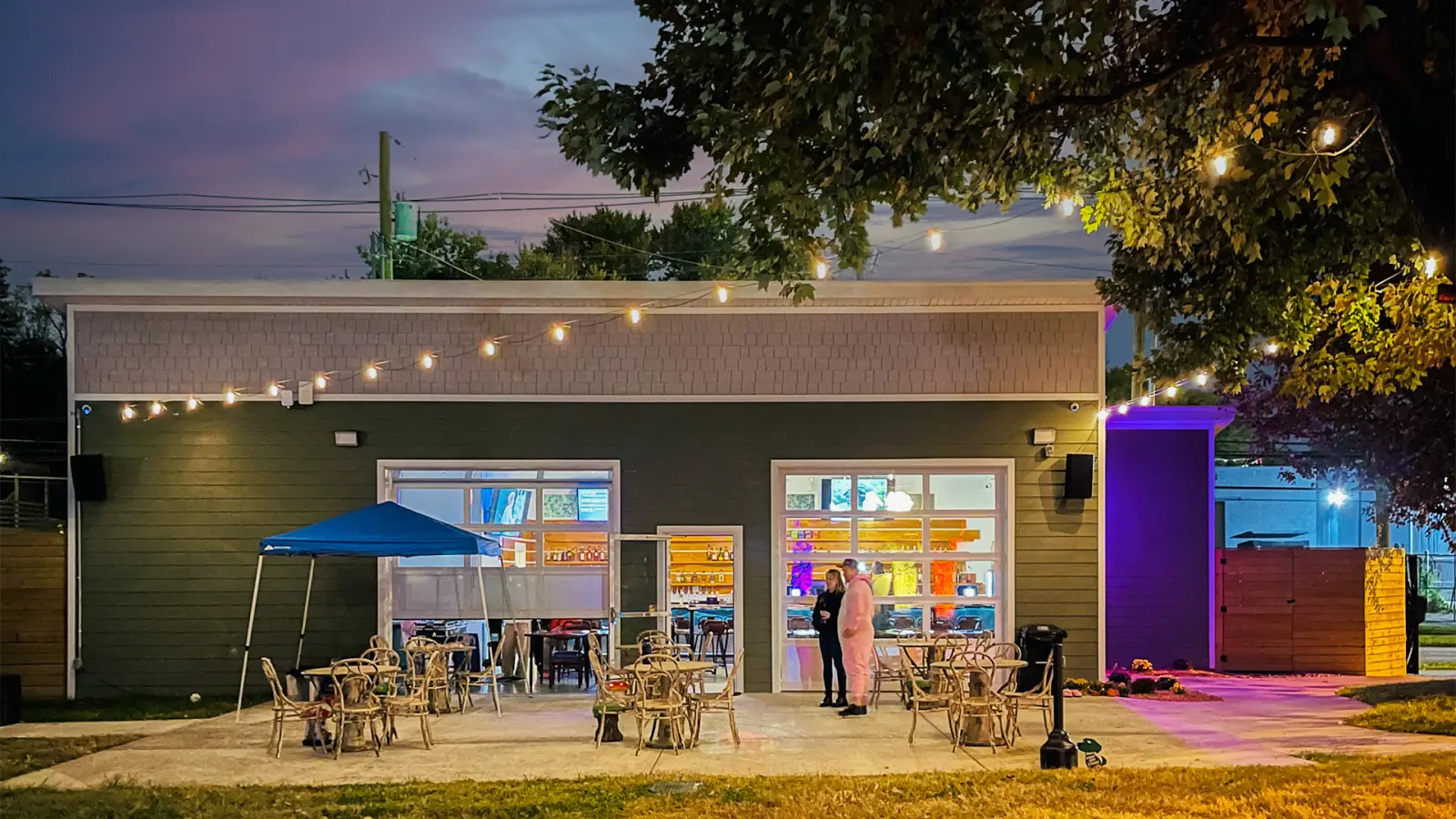 Field Bar at dusk with its garage doors open to the patio